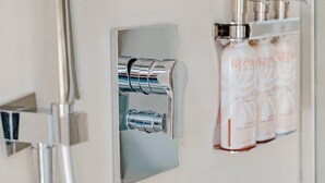 Eine Dusche mit Duschkopf und Seifenspender an der Wand.