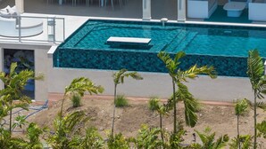 Ein modernes Haus mit Swimmingpool, Solaranlage und Terrasse mit Gartenmöbeln.