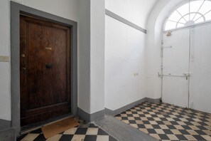 Ein Korridor mit kariertem Boden, einer Holztür und einer weißen Wand mit einem Fenster.