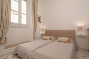 A bedroom with two beds, a window with curtains, bedside lamps, and a framed picture on the wall. - Experience the authentic charm of Florence in this elegant apartment located on Via Sant'Onofrio, in the historic Oltrarno district—one of the city's most charming, authentic, and sought-after neighborhoods.Blending contemporary design with carefully s (Firenze)