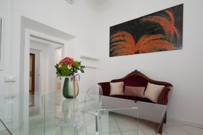 Ein modernes Interieur mit einem Glastisch, einem roten Sofa und einem an der Wand befestigten abstrakten Gemälde.
