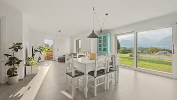 Ein moderner Essbereich mit einem weißen Tisch und Stühlen, einem blauen Schrank und Blick ins Freie.