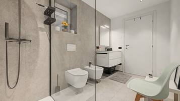 Un baño moderno con ducha, bidé e inodoro.