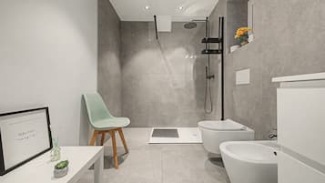 Ein modernes Badezimmer mit Dusche, Toilette, Bidet und einem kleinen Tisch mit Stuhl und einem gerahmten Bild.