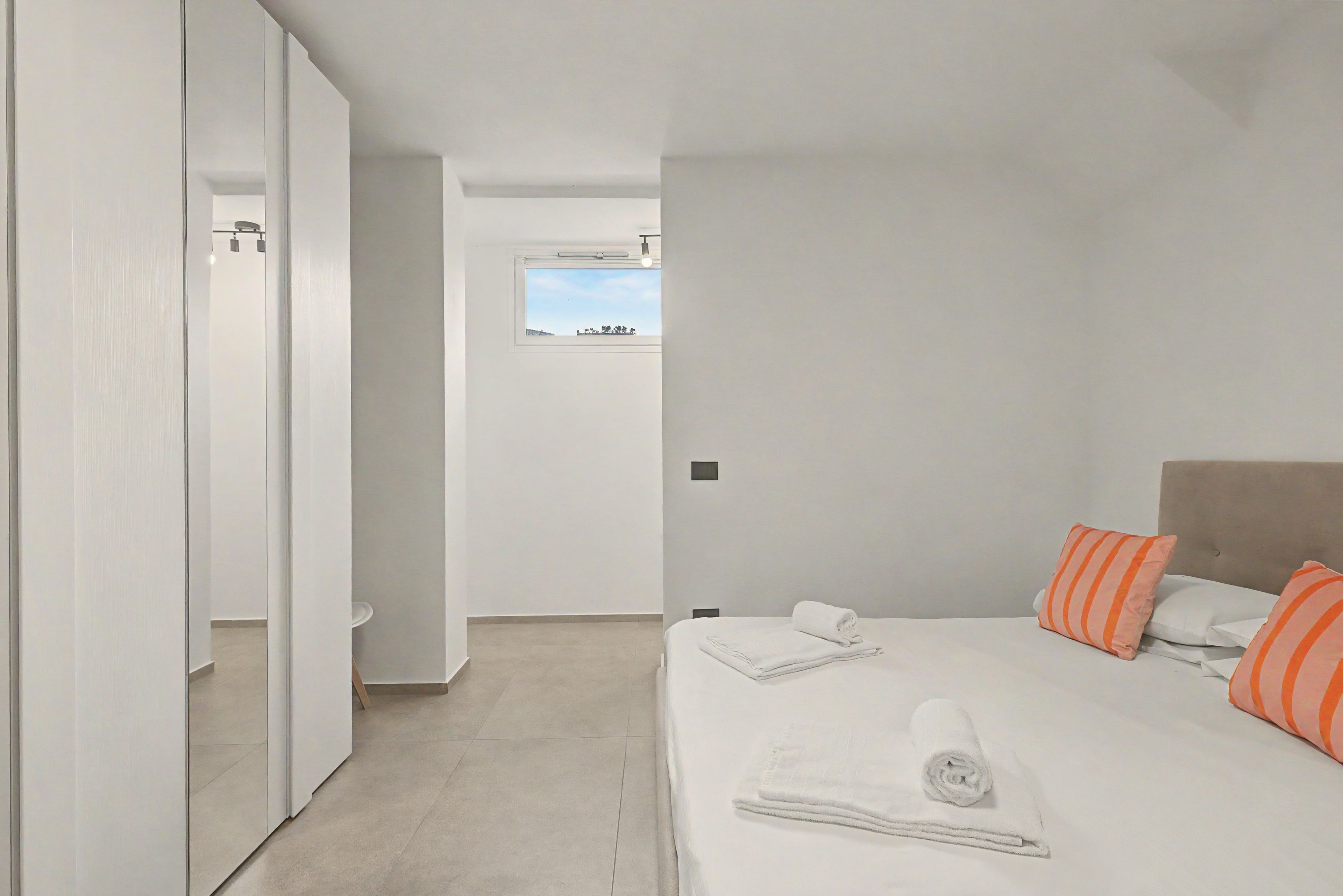 Un dormitorio con cama, almohadas, una ventana y una puerta.