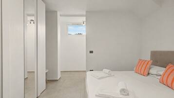 Un dormitorio con cama, almohadas, una ventana y una puerta.