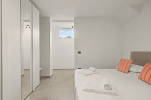 A bedroom with a bed, pillows, a window, and a door.