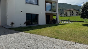 Una casa moderna de dos pisos amb un porxo cobert, un camí de grava i un jardí ben cuidat.