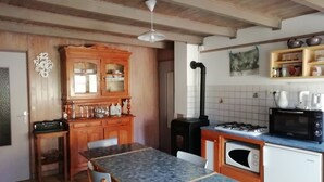 Una cucina con un armadietto in legno, un tavolo da pranzo con sedie, un fornello a gas, un forno a microonde e un lavello.