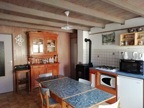 Eine Küche mit Holzschränken, einem Esstisch mit Stühlen, einem Gasherd, einer Mikrowelle und einem Spülbecken.