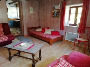 Une pièce avec un lit en bois, une chaise rouge, une table en bois et un canapé rouge.