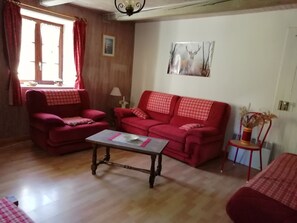 Ein Wohnzimmer mit einem roten Sofa, einem passenden Sessel, einem Holztisch und einem Bild an der Wand.