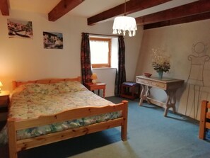 Ein Schlafzimmer mit einem Holzbett, einem Schreibtisch, einem Stuhl und einem Fenster mit Vorhängen.