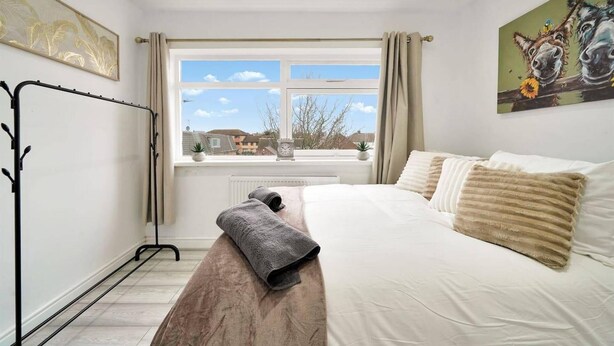 A bedroom with a bed, a window with curtains, a radiator, a clock, and a painting on the wall. - Belvedere 4-bed Apt, Sleeps 9 With Parking (Belvedere)