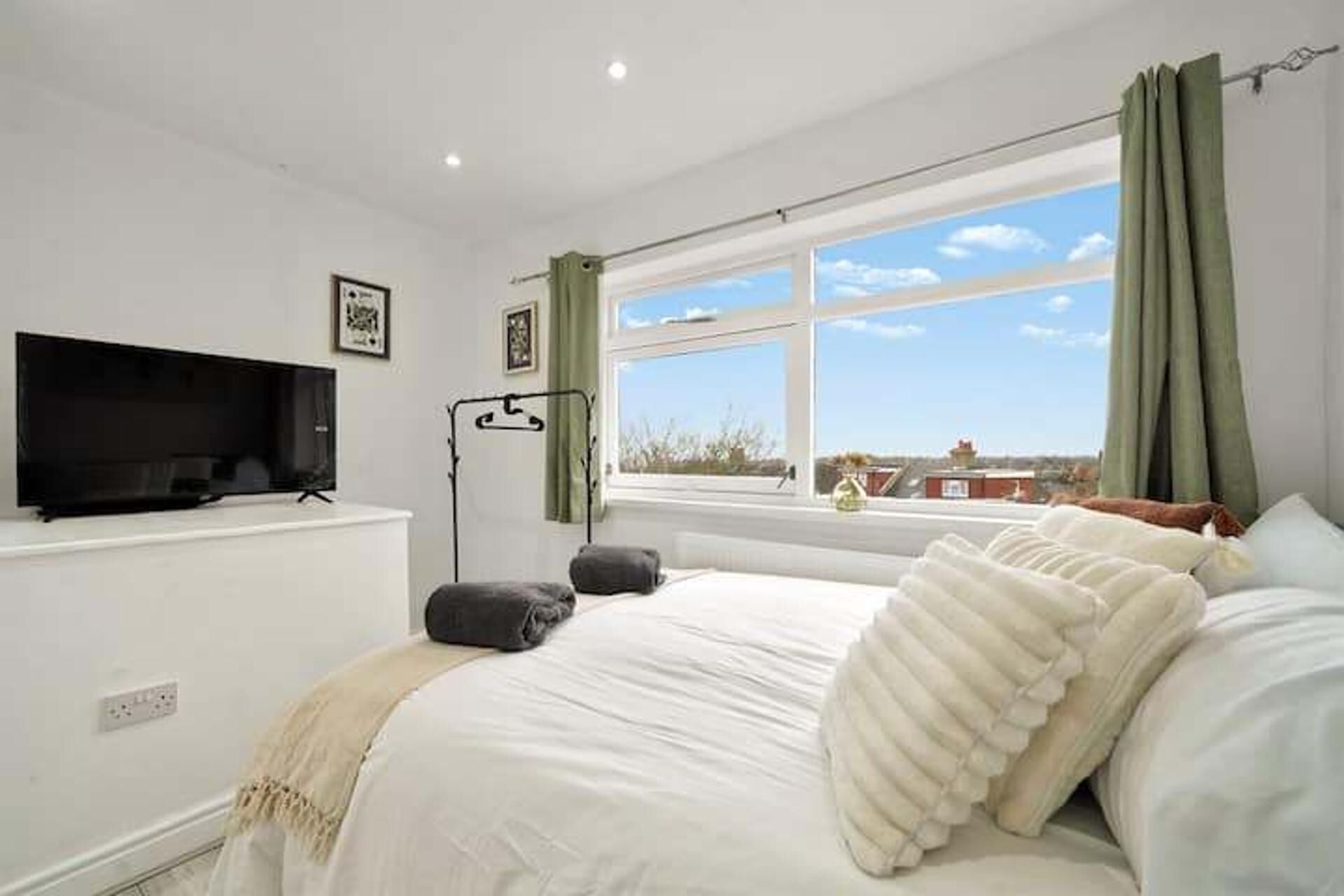 Une chambre à coucher avec un lit, une télévision, une fenêtre donnant sur un beau paysage et un rideau.