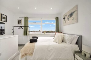 A bedroom with a bed, a desk, a window with curtains, and a world map on the wall. - Spacious 4-bedroom Apartment in Belvedere Sleeps 9 With Parking (Belvedere)
