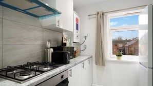 A compact kitchen with a gas stove, a microwave, and a small window with a view of buildings. - Belvedere 4-bed Apt, Sleeps 9 With Parking (Belvedere)