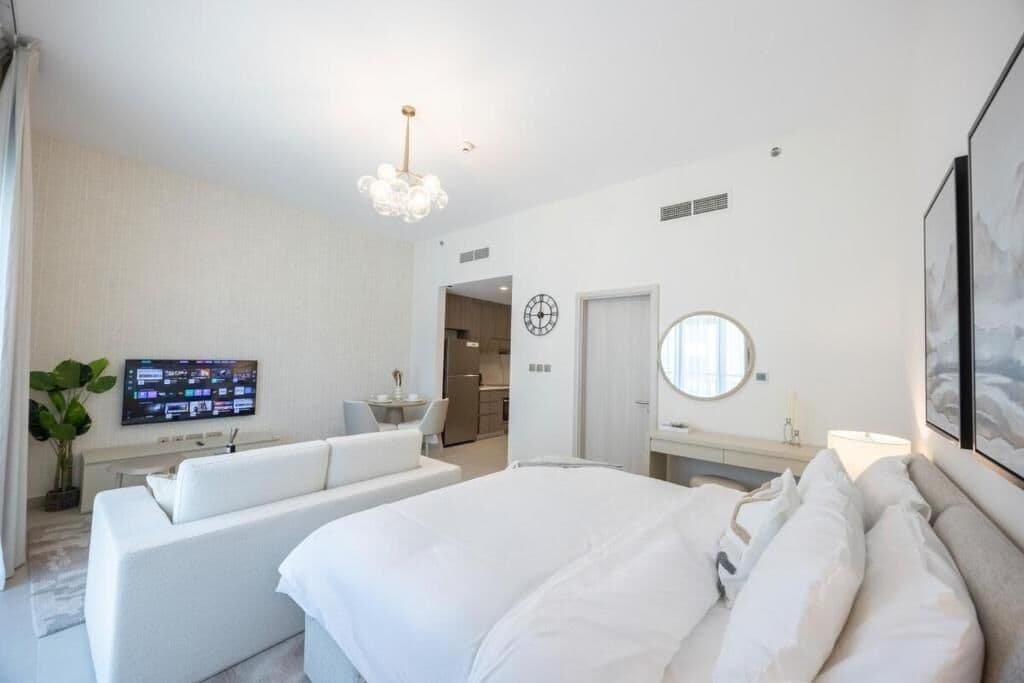 Ein Hotelzimmer mit einem Bett, einer Couch, einem Fernseher, einem Schreibtisch und einem Spiegel.
