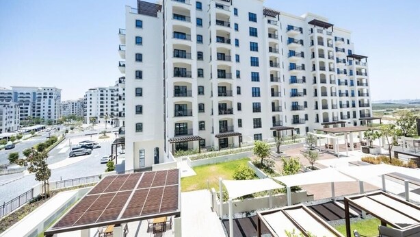 A multi-story residential building with balconies, a rooftop garden, and a parking area. - Bloomfields Studio in Fairways 3  (Abu Dhabi)