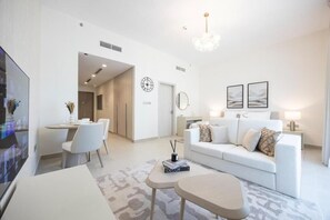 Ein modernes Wohnzimmer mit einem weißen Sofa, einem Essbereich mit Stühlen, einem Fernseher und einer Chandeliebre.