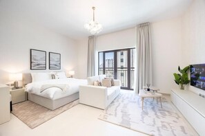 Ein modernes Schlafzimmer mit Bett, Sofa, Fernseher und einem Balkon mit Blick.