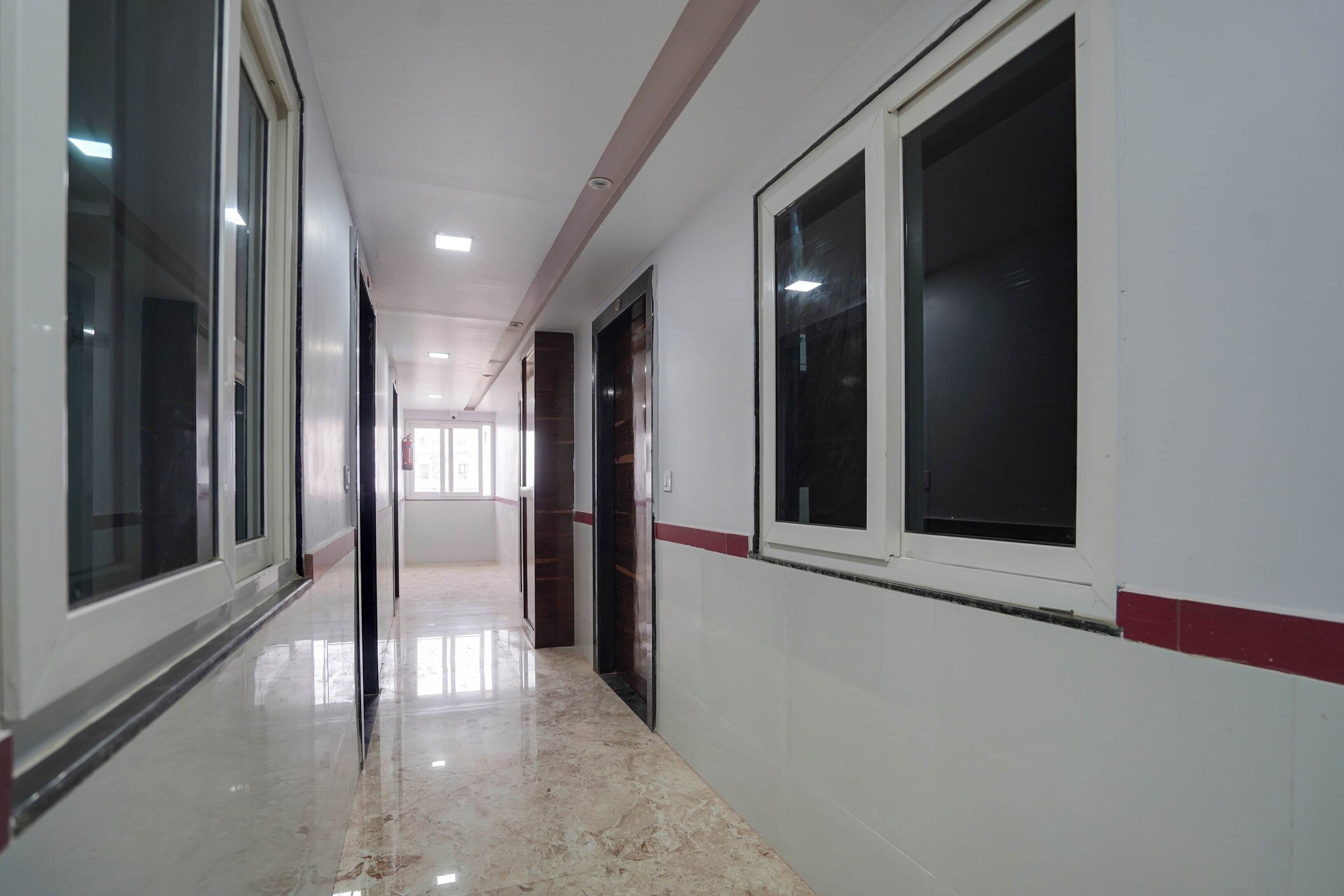 Un pasillo con piso pulido, ventanas amplias y puertas que dan a habitaciones.
