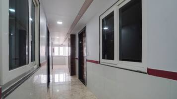 Un pasillo con piso pulido, ventanas amplias y puertas que dan a habitaciones.