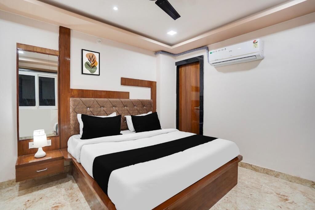 Un dormitorio con cama, mesita de noche, lámpara, equipo de aire acondicionado y un cuadro en la pared.