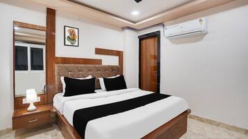 Un dormitorio con cama, mesita de noche, lámpara, equipo de aire acondicionado y un cuadro en la pared.