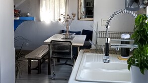A compact kitchen with a sink, a dining area with a table and chairs, and a window with curtains. - Waterfront fisherman's cottage in a nature reserve; pets welcome (Sigean)
