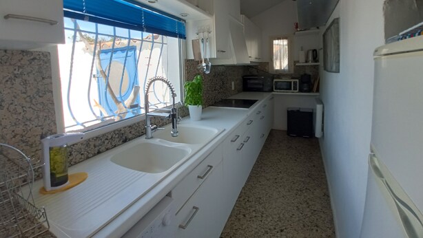 Cocina compacta con ventana, lavamanos, microondas y refrigerador.