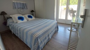 Un dormitorio con cama, ventana, ventilador y puerta.