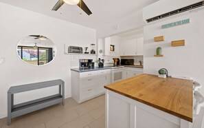 Eine moderne Küche mit weißen Schränken, einer Holz Arbeitsplatte, einem eingebauten Backofen und einem Deckenventilator.