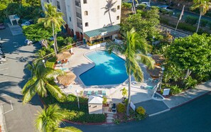 Eine Vogelperspektive eines Resorts mit Schwimmbad, Palmen und einem Gebäude mit Balkonen.