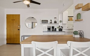 Eine moderne Küche mit weißen Schränken, einem Holztisch und einem Deckenventilator.