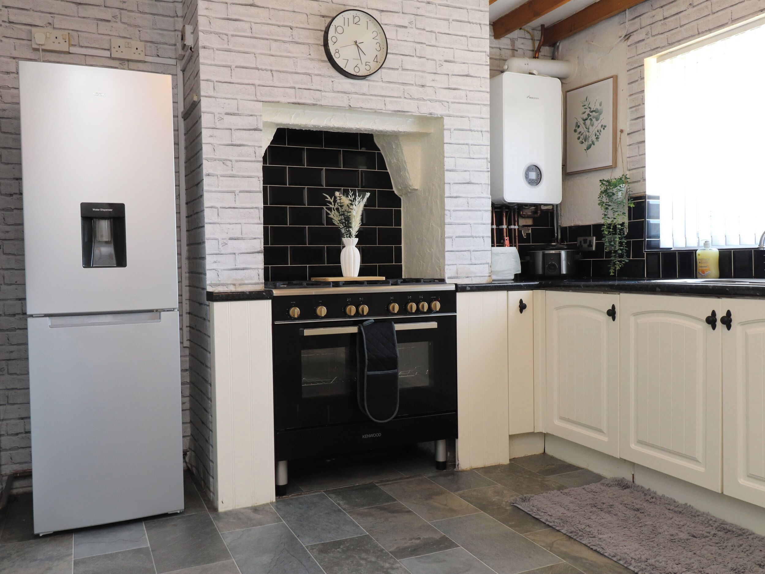 A kitchen with a white refrigerator, black stove, and white cabinets.