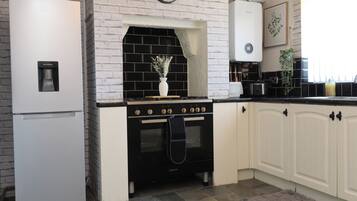 A kitchen with a white refrigerator, black stove, and white cabinets.