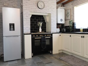 A kitchen with a white refrigerator, black stove, and white cabinets.