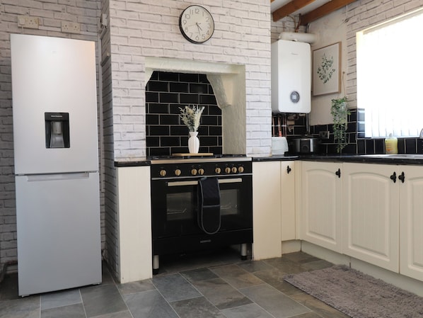 Una cocina con refrigerador blanco, estufa negra y alacenas blancas.