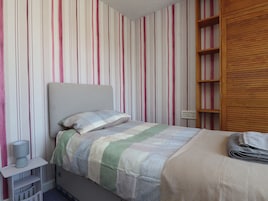 Un dormitorio con cama, mesita de noche, lámpara y armario de madera.