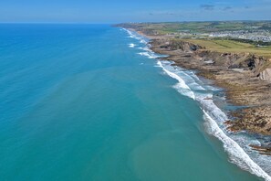 A coastal landscape with a beach, cliffs, and a distant town. - Perrantide (Upton)