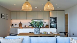 Cocina moderna con zona de comedor, que incluye iluminación colgante, una isla central y un espacio para sentarse.