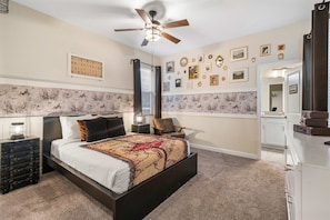 A bedroom with a bed, a ceiling fan, a nightstand, a dresser, and a door labeled 'ROOM REQUIREMENT'. - 1576 Flange Drive (Davenport)
