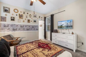 A bedroom with a bed, a white dresser, a television, and a wall decorated with framed photos and a mirror. - 1576 Flange Drive (Davenport)