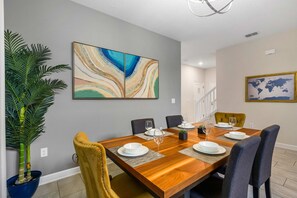 A dining area with a wooden table, chairs, and a large abstract painting on the wall. - 1576 Flange Drive (Davenport)