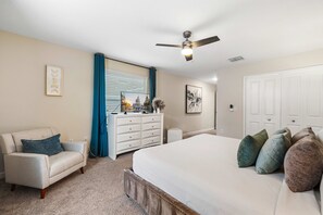 A bedroom with a bed, a chair, a dresser, a ceiling fan, and a window with curtains. - 1576 Flange Drive (Davenport)