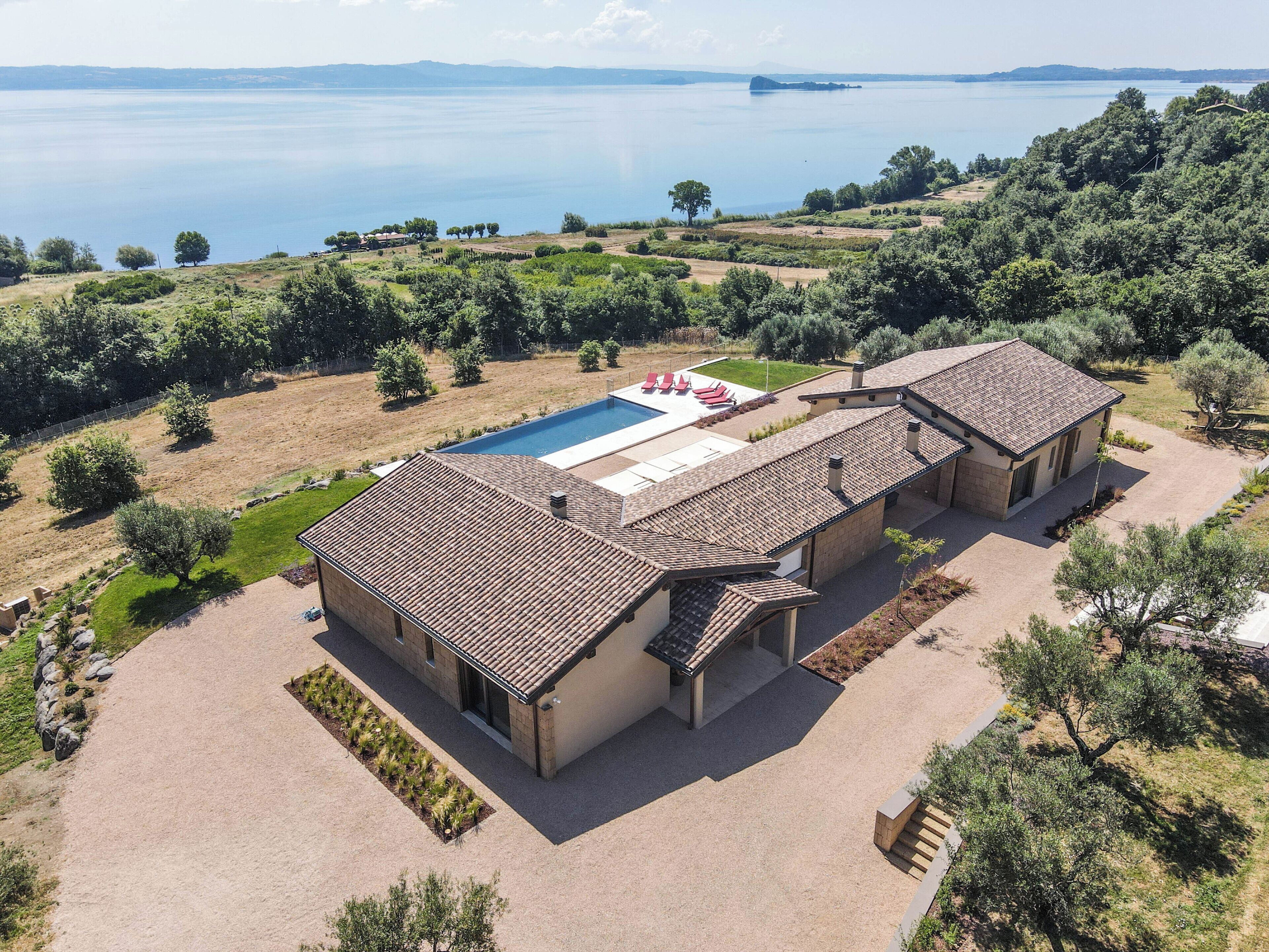 A villa with a swimming pool, multiple rooms, and a view of the lake.