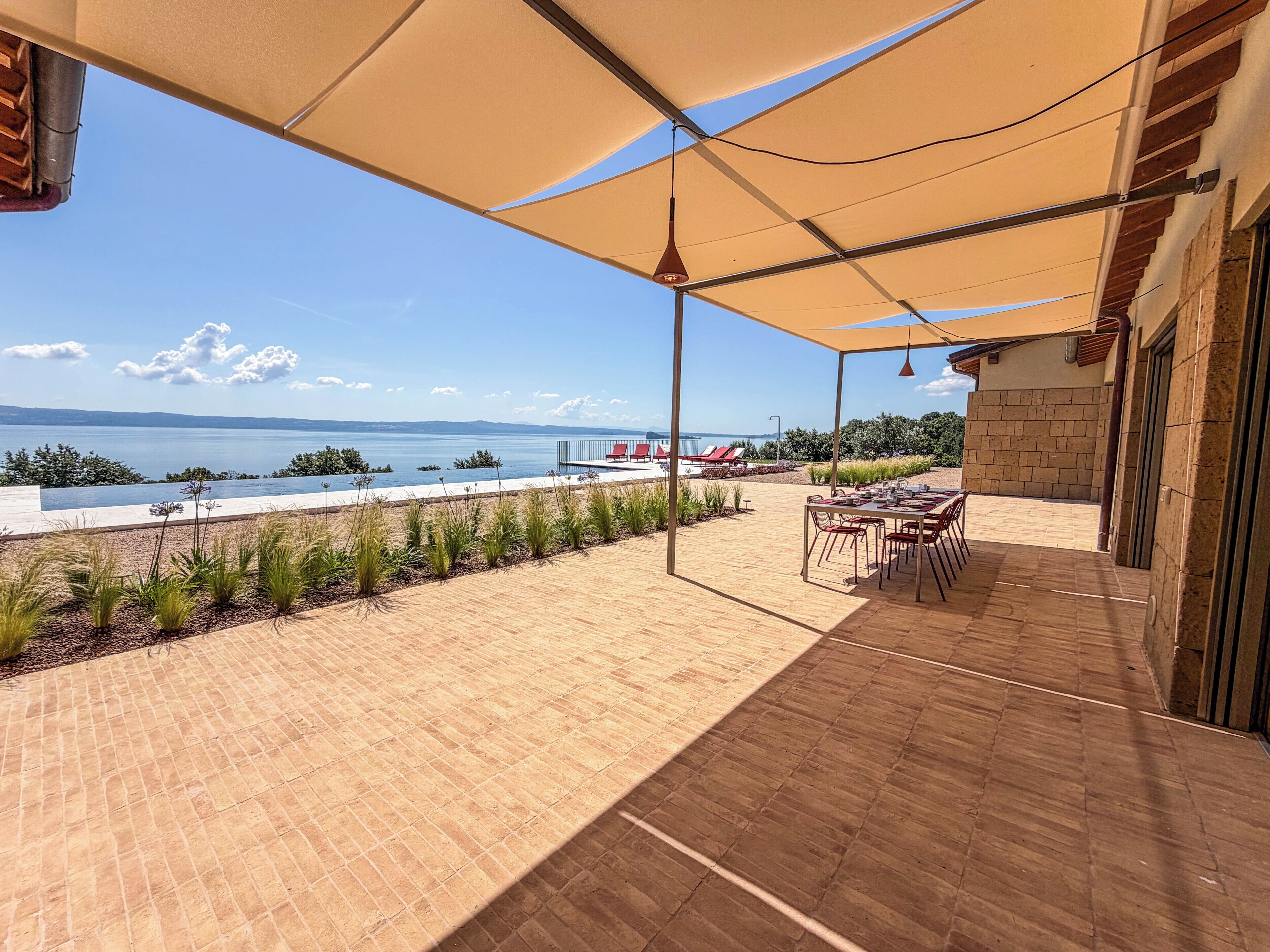 A patio with a view of the sea, outdoor seating, and a pool.