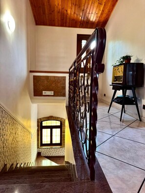 Eine Treppe mit hölzernem Geländer, einer an der Wand befestigten Uhr und einem kleinen Blumentopf.