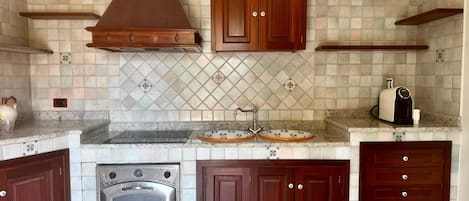 Uma cozinha com forno embutido, fogão, armários de madeira e painel de azulejos.